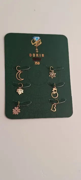 نمایی از چند پلاک آویز ظریف طلایی روی کارت سبز با نشان ۷۵۰